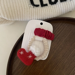 Dettaglio di elastico con guanto invernale e scrunchie rosso su cartoncino regalo