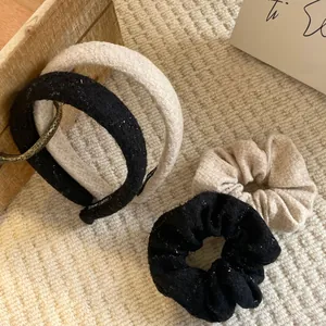 Close-up of black and beige tweed headbands and scrunchies set on a wooden tray