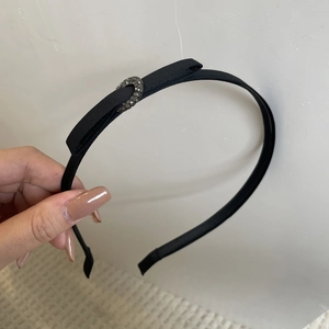 Détail d'un serre-tête en tissu noir élégant avec un nœud et des strass en croissant