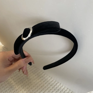 Détail d'un serre-tête en velours noir avec texture douce et anneau métallique argenté
