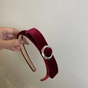 Détail d'un serre-tête en velours bordeaux avec une boucle en métal argenté élégante