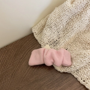 Barrette à cheveux rose plissée en tissu de laine épais sur un fond en bois rustique