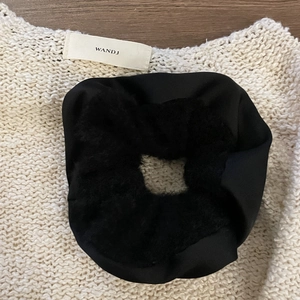 Furry black oversized scrunchie for ponytails on white knitted background textures