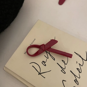 Elegant red bow hair clip made of acetate on a beige book cover in vintage style