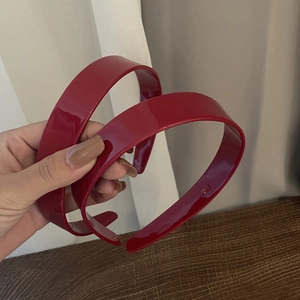 Glossy dark red acetate hairband set of two held by hand for daily hair styling