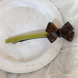 Detailed view of 3D acetate bow hair clip with tortoiseshell pattern and green base