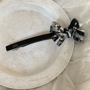 Handmade acetate 3D bow hair clip in black and marble pattern on ceramic tray