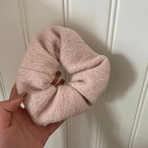 Close-up of a large fluffy pink plush scrunchie showing soft knitted fabric texture
