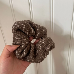 Close-up of a plush dark brown scrunchie with soft white fiber accents for autumn and winter