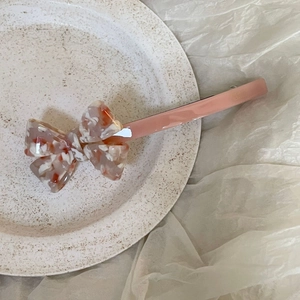 Pink acetate bow hair clip for women with elegant marble texture on a ceramic plate