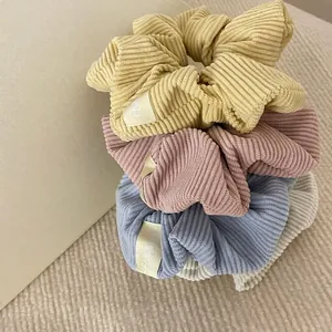 Pastel corduroy hair scrunchies in cream and blue stacked on knit fabric