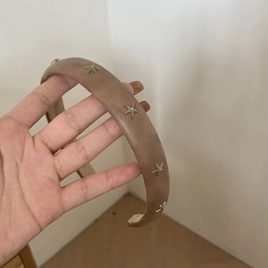 Brown wide sponge headband with decorative golden metal starfish accents in hand