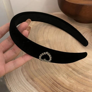 Detail of a black velvet hair clip with a sparkling rhinestone heart on a wooden surface