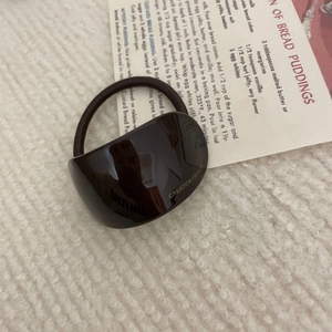 Detail of French style chocolate hair scrunchie with a gold labeled resin block