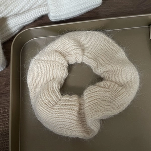 Soft knit mohair scrunchie in beige placed on a gold tray for a cozy winter look