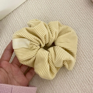 Detailed close-up of light yellow corduroy scrunchie fabric texture and branded label