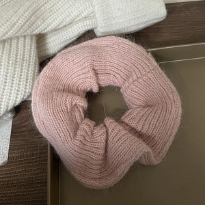 Detailed close-up of pink mohair knit scrunchie texture in a warm aesthetic setting