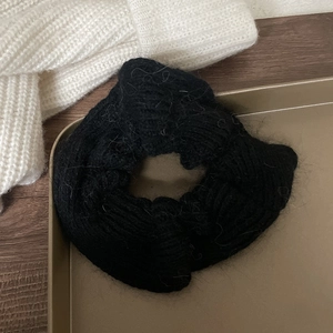 Detailed close-up of a soft black mohair knit scrunchie with fluffy texture in a tray