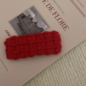Dettaglio del fermaglio per capelli in maglia rossa con trama di lana su sfondo art