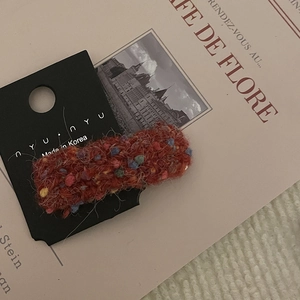 Dettaglio del fermaglio per capelli rosso in peluche con fibre colorate su carta