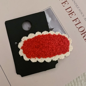 Dettaglio del fermaglio per capelli in peluche rosso con bordi in pizzo bianco all'uncinetto