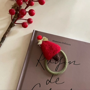 Chouchou de Noël fait main en feutrine avec bonnet de Père Noël sur livre