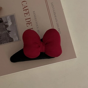 Dettaglio di un fermaglio per capelli con fiocco di velluto rosso su rivista d'epoca