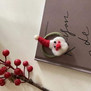 Gros plan d'un élastique de Noël en feutre fait main posé sur un livre de décoration