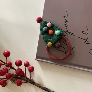 Détail d'un élastique à cheveux sapin de Noël en feutre vert avec pompons multicolores