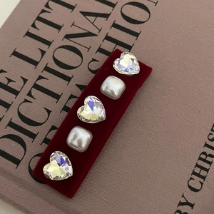 Dettaglio fermaglio in velluto bordeaux con strass a cuore e perle sopra un libro