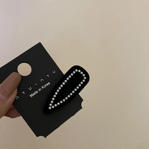 Elegant black flocked hair clip with pearl embellishments on a display card