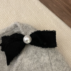 Eleganter Tweed-Haarclip mit Schleife und Perle auf einem gestrickten Texturhintergrund