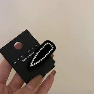 Elegant black velvet hair clip with sparkling white rhinestones on display card