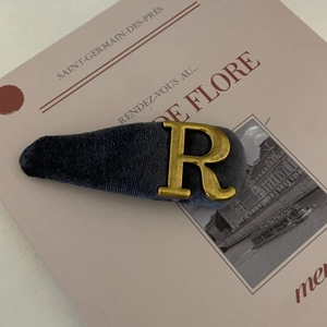 Grey velvet hair clip with gold metal letter R on a French aesthetic background