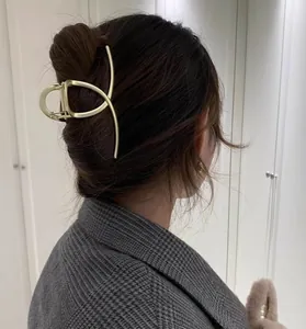 Detail of matte gold metal shark hair claw clip styled on a model in a messy bun