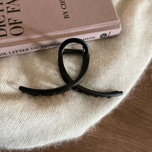 Minimalist matte black metal hair claw clip displayed on an aesthetic lifestyle background