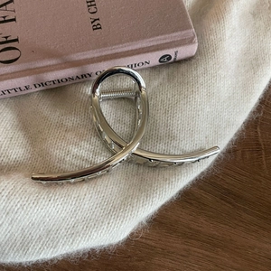 Close-up of polished silver metal shark hair claw clip on soft knit sweater