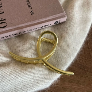 Close-up of golden matte hair claw clip on knit sweater with fashion book detail
