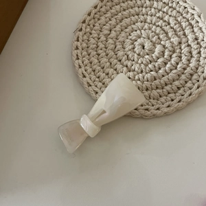 Dettaglio della clip per capelli in acetato bianco crema con incisione dorata