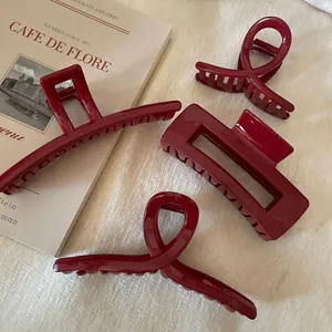 Set of four glossy burgundy hair claws in various shapes on a minimalist beige fabric