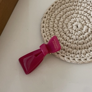 Dettaglio di un fermaglio per capelli a fiocco fucsia brillante con finitura lucida