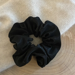 Elegant black faux leather scrunchie hair tie with vintage matte texture on wood