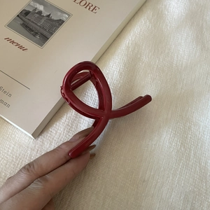 Detailed view of the dark red twisted hair claw clip held in hand for size visualization