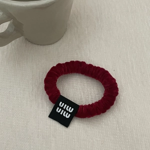 Detailed close-up of wine red velvet hair scrunchie with a black square woven label