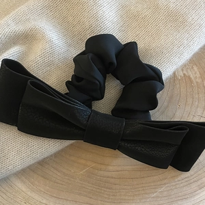 Elegant black velvet bow scrunchie on a rustic wooden tray with knitted background fabric