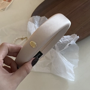 Elegante cerchietto in raso champagne con fibbia dorata e dettaglio dell'etichetta