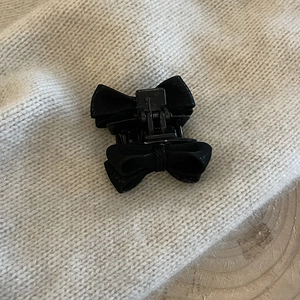 Close-up of black velvet bow hair claw clip on soft knitted background, elegant french style