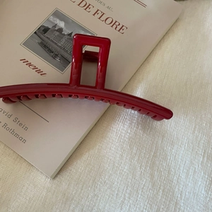 Close-up of a glossy red shark hair clip with teeth design on a cafe menu background