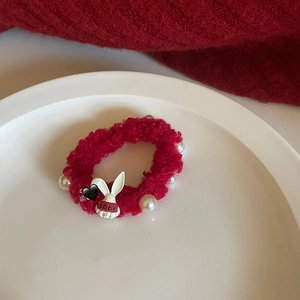 Detail view of a cute plush rabbit hair tie featuring white faux pearls and a red band