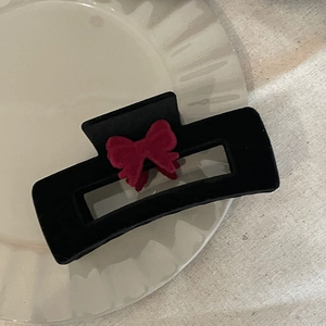 Vue détaillée d'une pince à cheveux rectangulaire en velours avec un nœud rouge